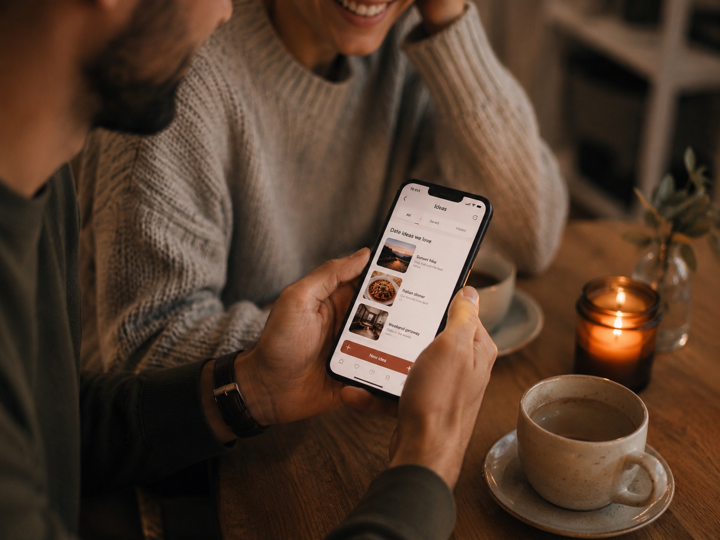 Hands holding a phone in a cozy date setting
